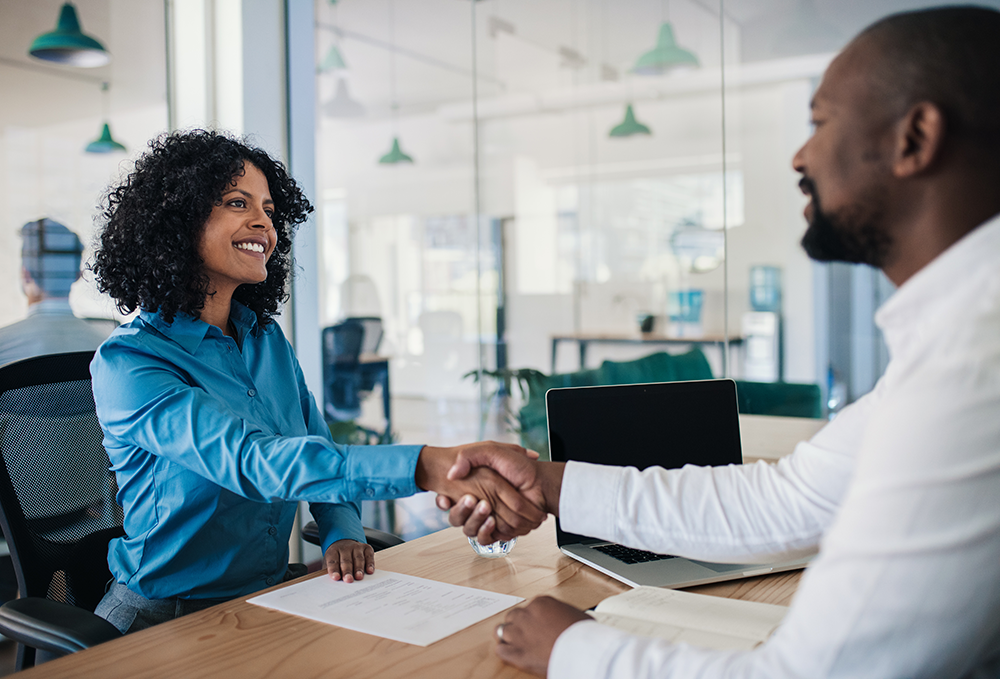 Imagem de uma entrevista de emprego que revela o que os recrutadores observam além do currículo: postura, atitude e confiança na interação pessoal.